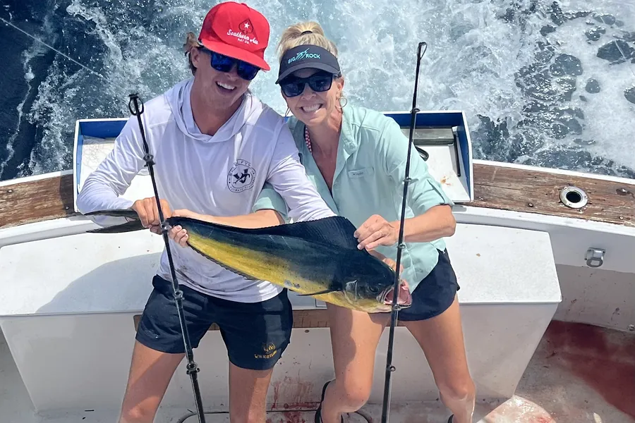Two anglers holding a mahi-mahi at the stern