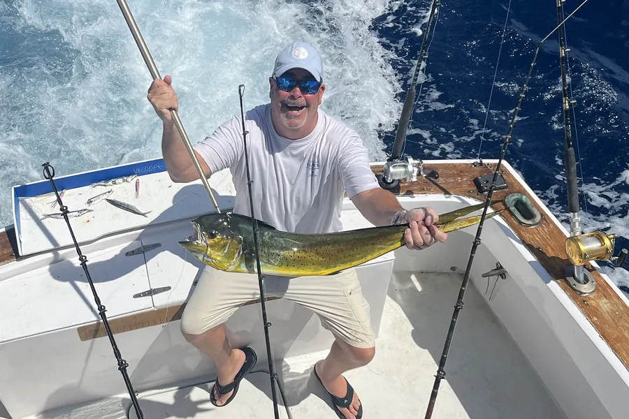 Smiling angler holding a mahi-mahi in the cockpit offshore