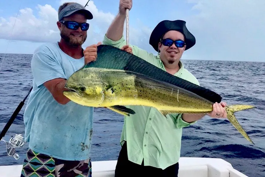 Two anglers holding a mahi-mahi aboard a Key West charter boat