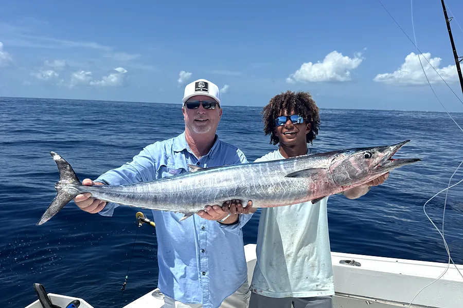 Anglers holding a large wahoo caught on a Key West fishing trip