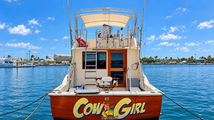 The Cowgirl – stern view with the COW GIRL transom graphic, fighting chair and flybridge, moored in Key West harbor
