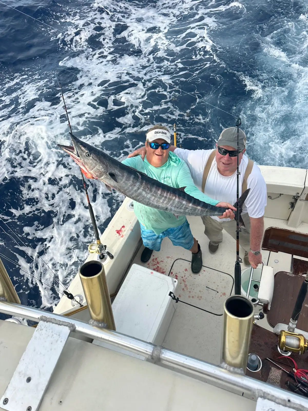 Two anglers holding a large wahoo on the boat deck
