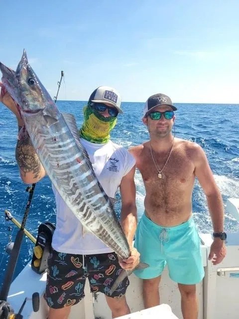 Smiling customer holding a freshly caught wahoo aboard a Key West fishing charter boat during a deep sea fishing trip in Florida.