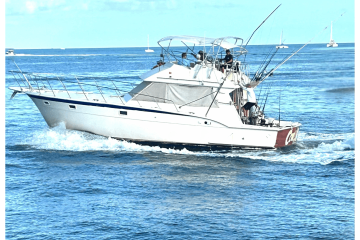 The 45‑foot Hatteras ‘Cowgirl’ sportfishing boat docked in Key West, Florida, with its white hull, twin diesel engines, air‑conditioned cabin windows, and tournament‑grade fishing outriggers against a backdrop of turquoise water and clear sky