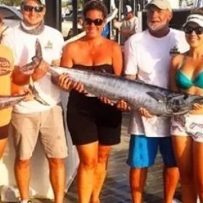 Group of anglers on a shared Key West fishing charter holding several wahoos and smiling together