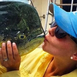 Woman kissing a large mahi mahi after a successful offshore fishing trip with Cowboy Cowgirl Sportfishing in Key West