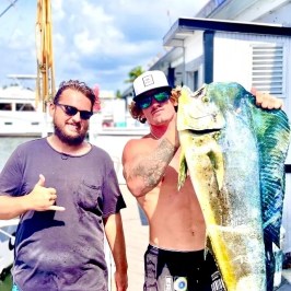a group of people standing next to a person holding a fish
