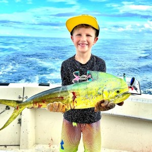a young boy holding a fish in the water